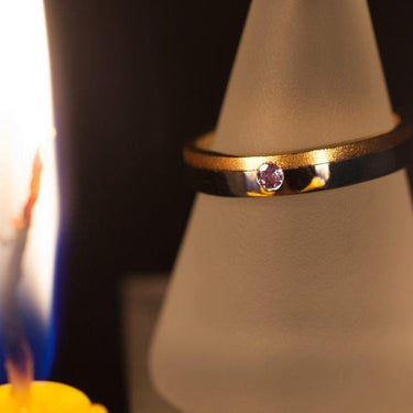 White and yellow gold wedding band with round brilliant cut natural alexandrite stone, matte yellow gold finish with polished white gold accents.